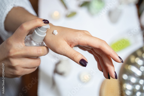 Cropped photo of young lady applying cream on her skin