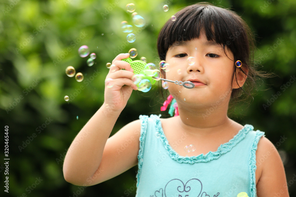 A little girl blowing soap bubbles in garden A little girl blowing soap bubbles in garden