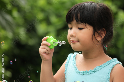 A little girl blowing soap bubbles in garden 