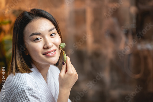Asian charming lady posing for camera with facial massager