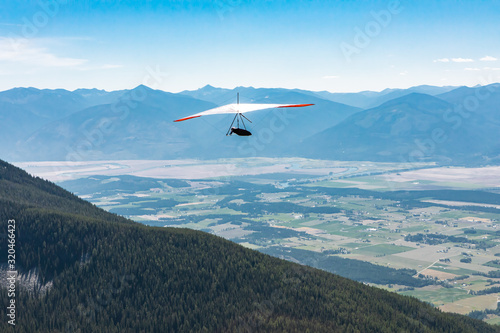 Back view of person Hang-gliding. Professional air sportsman enjoying his recreational journey to Creston, British Columbia, Canada