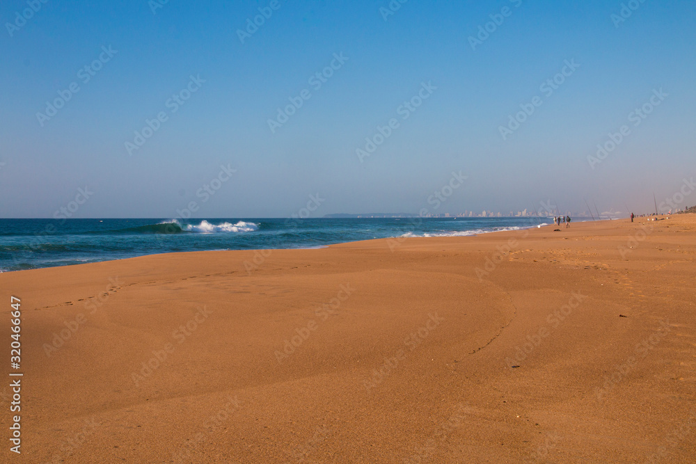 Stretch of Clear Beach Sand with Fishrmen and Buildings in Background