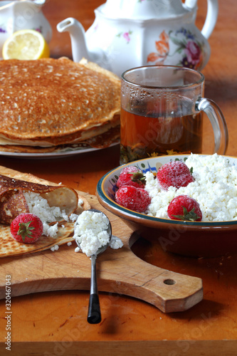 Still life with pancakes, sour cream, honey, cottage cheese, viburnum and samovar