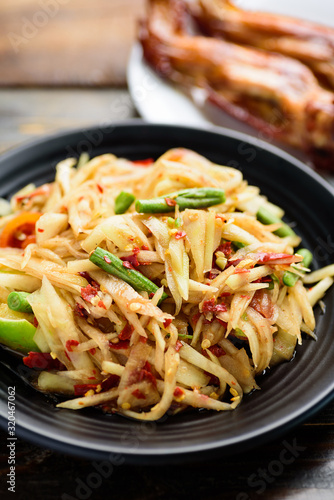 Thai food (Som Tum), spicy green papaya salad eating with grilled chicken wing