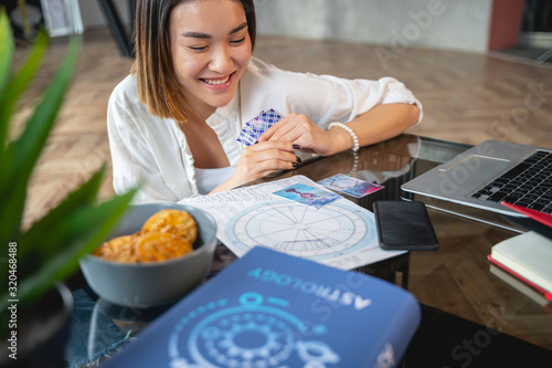 Asian pretty girl analysing her horoscope indoors