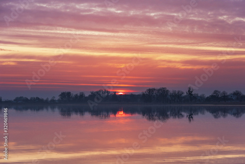 Landscape evening with sunset on a lake with lilies, with beautiful sky in summer season 