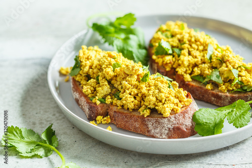 Photos Tofu scramble sandwich on a gray plate. Vegan food concept.