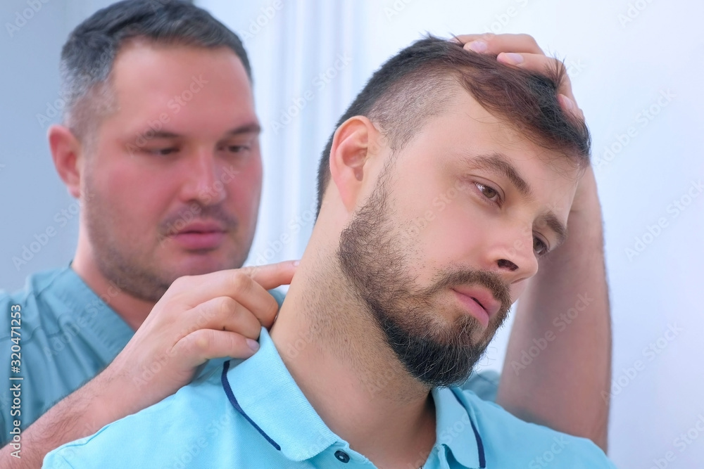 Portrait of man on preventive examination of doctor chiropractor on neck diagnostic. Manual therapist turning patient's head in different sides to make a diagnosis and find problem. Manual physician. Portrait of man on preventive examination of doctor chiropractor on neck diagnostic. Manual therapist turning patient's head in different sides to make a diagnosis and find problem. Manual physician.
