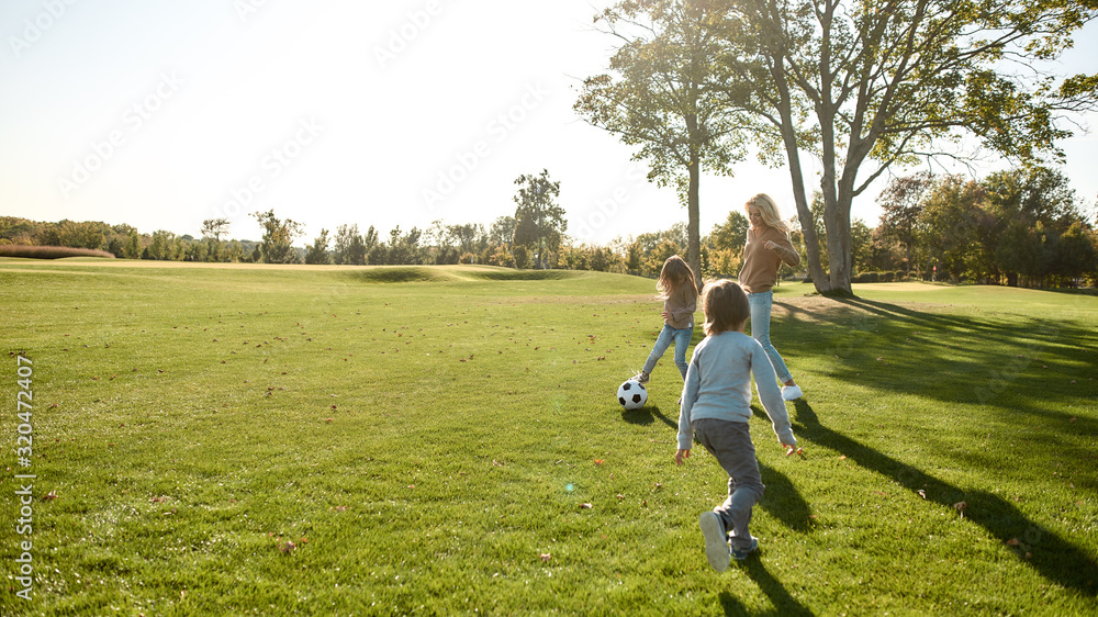 Affordable family fun. Happy family playing with a ball on meadow