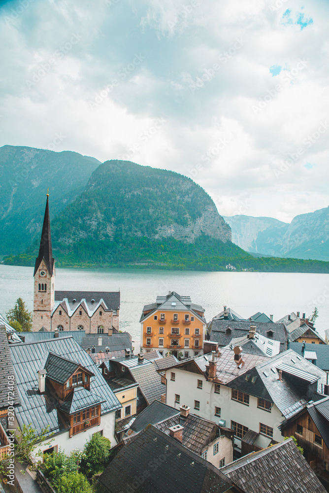 Fototapeta premium hallstatt church with bell tower lake with alpine mountains on background