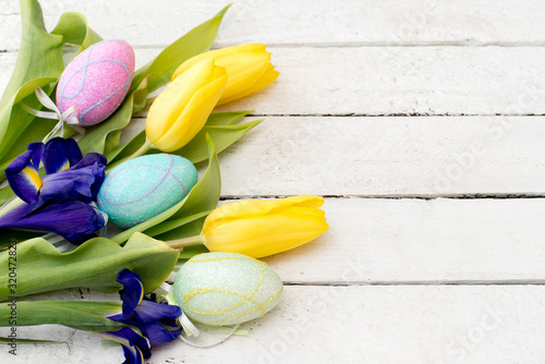 Easter eggs and sprind flowers on wooden planks with a copy space