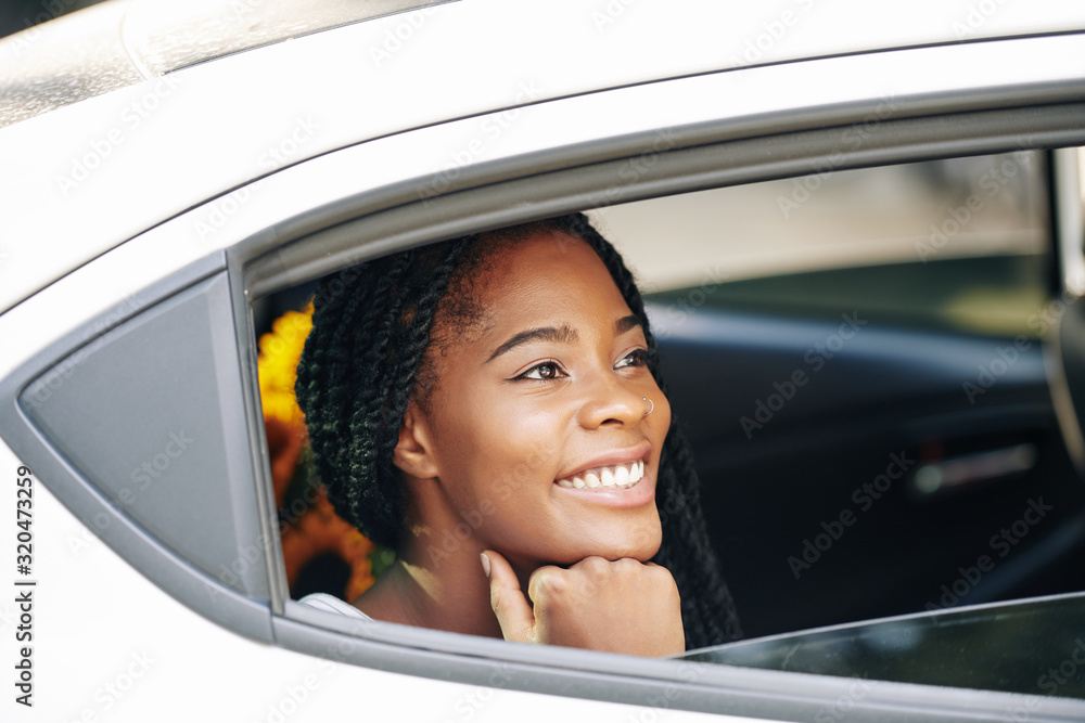 Beautiful young Black woman smiling and looking through opened car window