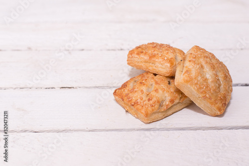 Three cookies with sesame on wooden background with a copy space