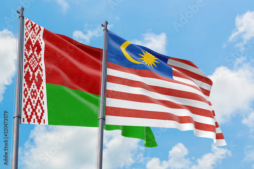 Malaysia and Belarus flags waving in the wind against white cloudy blue sky together. Diplomacy concept  international relations.