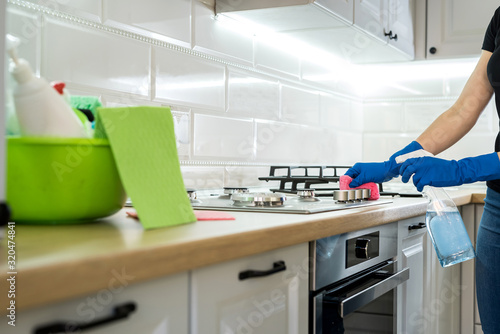 young woman cleaning in rubber gloves and sponge in the kitchen at home