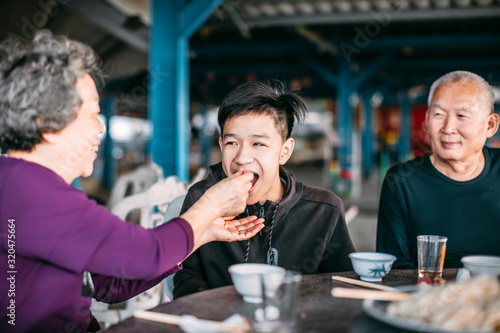 Grandmother feeding her teenager grandson in restaurant