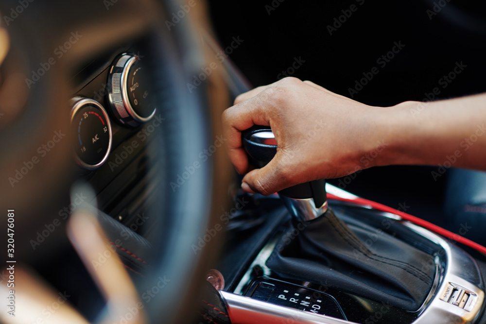Close-up image of woman smoothly changing gear when driving her new car