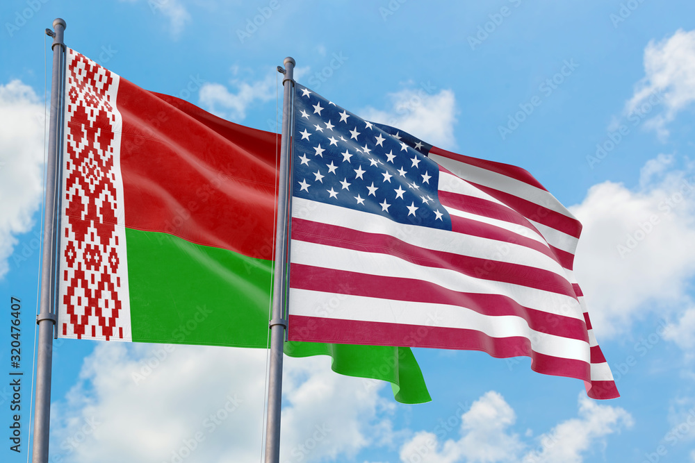 Obraz premium United States and Belarus flags waving in the wind against white cloudy blue sky together. Diplomacy concept, international relations.