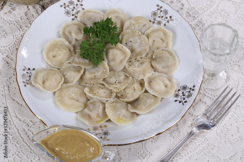 Hot Siberian dumplings with greens on a white plate