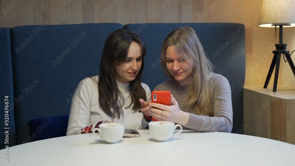 Female Friends Social Networking at a Cozy Cafe while Drinking Coffee. Social Media Sharing Online Concept Female Friends Social Networking at a Cozy Cafe while Drinking Coffee. Social Media Sharing Online Concept