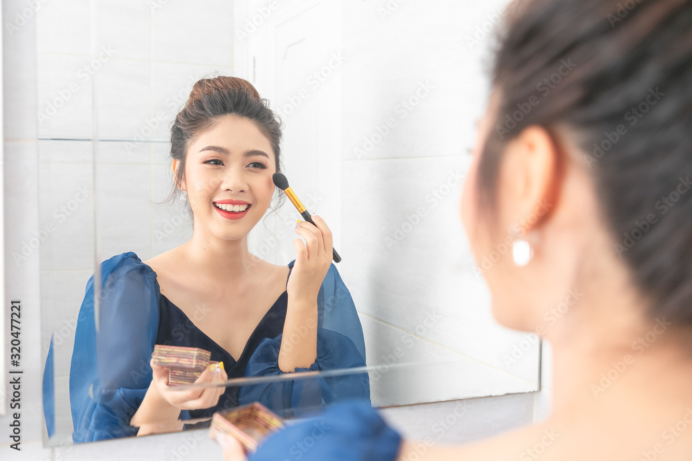 Portrait of a beautiful asian woman as applying makeup near a mirror. Portrait of a beautiful asian woman as applying makeup near a mirror.