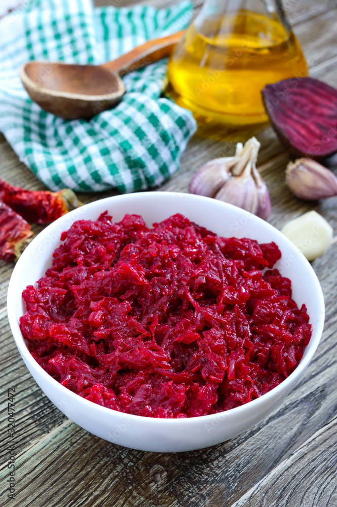 Beetroot caviar. Simple, tasty and healthy vegetable snack in a white bowl on a wooden table. Lenten menu. Vertical view Beetroot caviar. Simple, tasty and healthy vegetable snack in a white bowl on a wooden table. Lenten menu. Vertical view