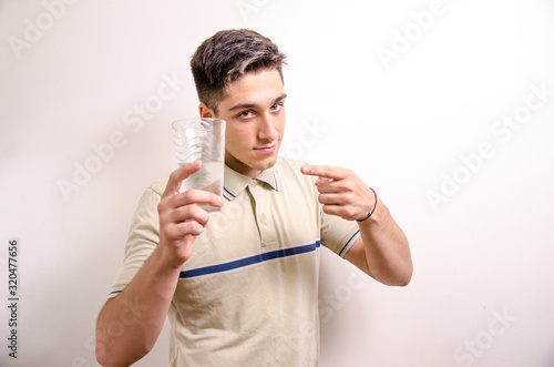 Young man showing a glass of water 