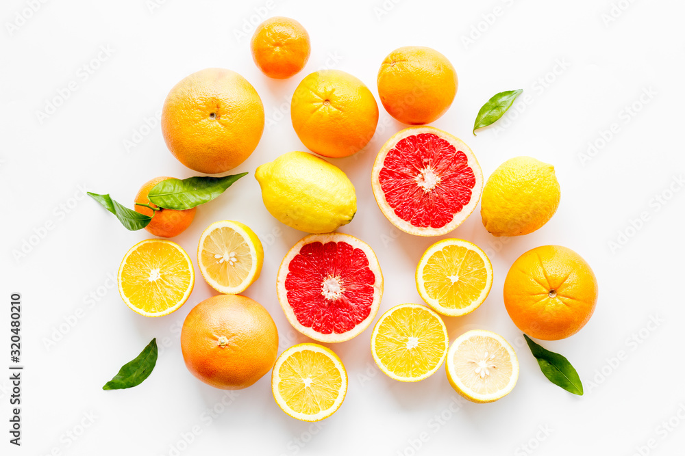 Fresh citrus background. Oranges, grapefruits, leaves - whole fruits and halfs - on white background top-down Fresh citrus background. Oranges, grapefruits, leaves - whole fruits and halfs - on white background top-down