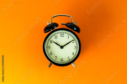 old vintage alarm clock on orange background