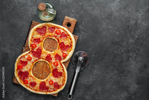 Pizza in the form of 8 on chopping chalkboard for International Women's Day March 8 on a stone background. with copy space for your text. March 8 celebration concept.