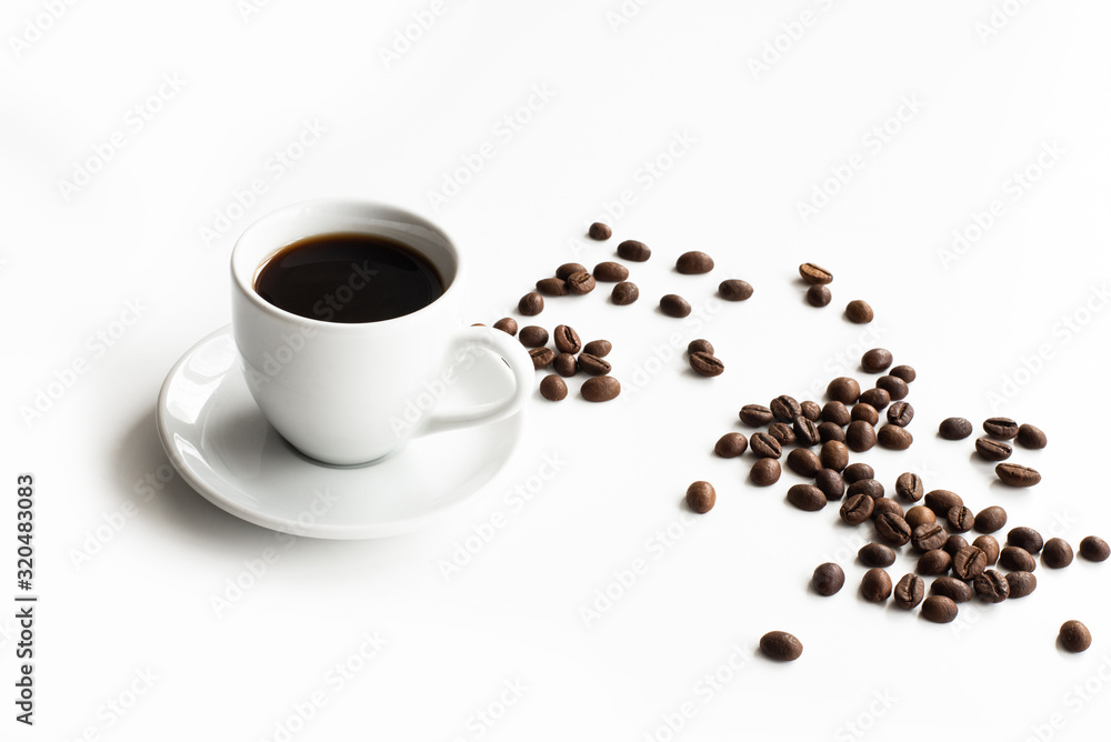 White cup of coffee and saucer on a white table scattered coffee grains with place for text top view White cup of coffee and saucer on a white table scattered coffee grains with place for text top view