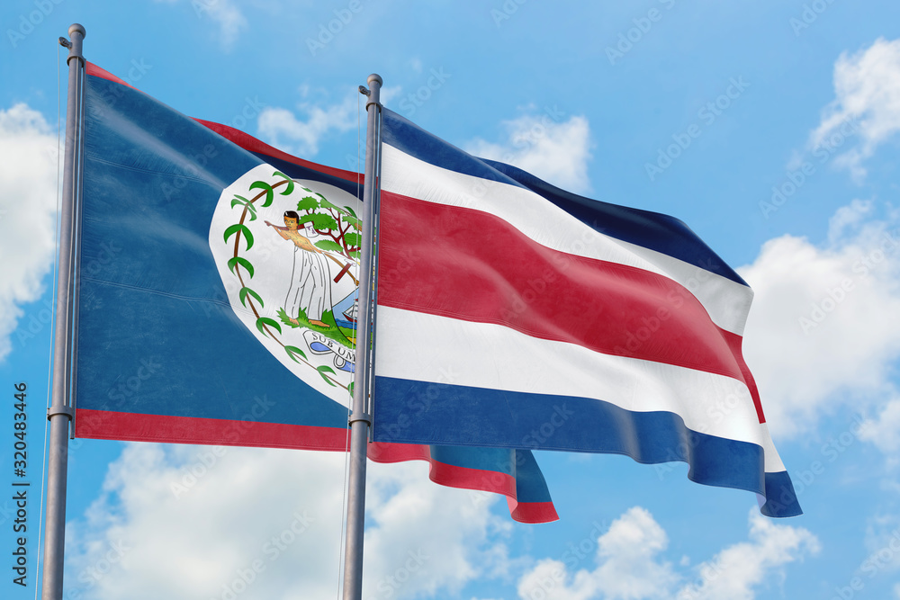 Costa Rica and Belize flags waving in the wind against white cloudy blue sky together. Diplomacy concept, international relations.