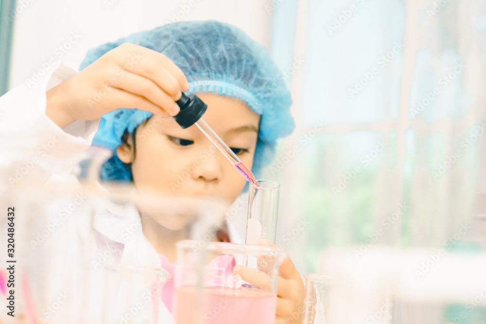 Asian little girl playing with fun as a scientist working in a lab equipped with colored glass tubes. Asian little girl playing with fun as a scientist working in a lab equipped with colored glass tubes.