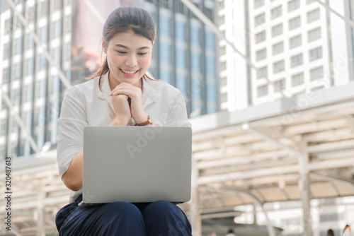 Foto Asian businesswoman is sitting happily and successfully working with a laptop