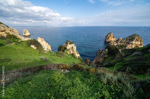 Scenic natural cliff formations of Algarve coastline with green grass at Ponta da Piedade, in Algarve Portugal