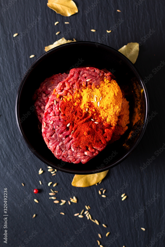 Food preparation ingredients concept organic raw minced or ground beef marinated with spices for oriental food Keema curry on black slate stone with copy space