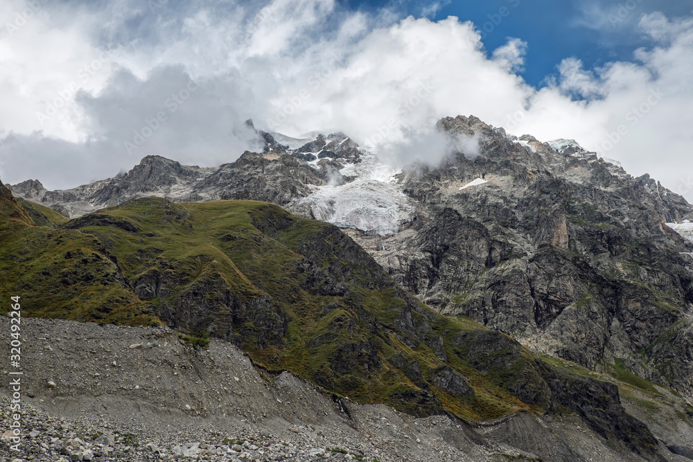 Rocky mountain with small glacier on it and top hiding in clouds Rocky mountain with small glacier on it and top hiding in clouds