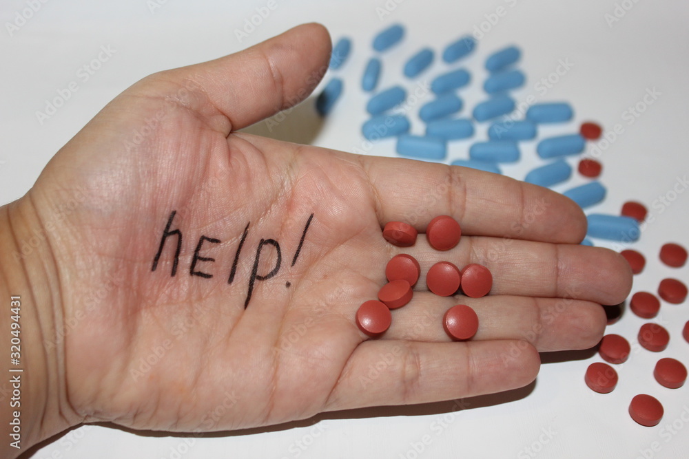 The inscription Help on the hand against the background of pills. Sick person needs help The inscription Help on the hand against the background of pills. Sick person needs help
