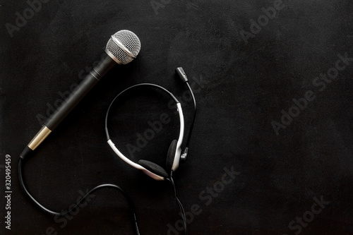 Television concept. Microphone and headset on black background top-down copy space