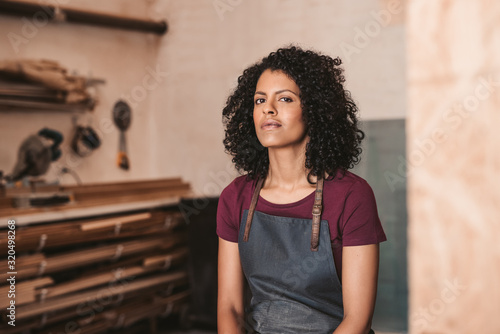 Confident young woman sitting in her framing workshop