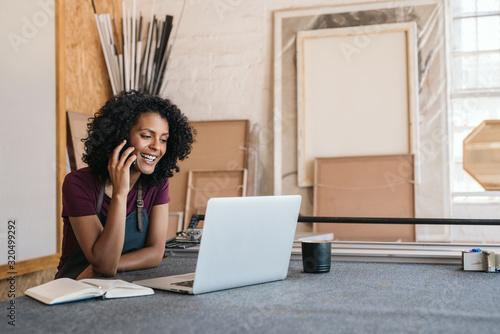 Foto Smiling woman talking on the phone in her framing studio