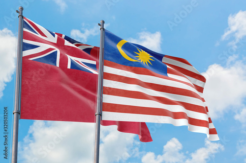 Malaysia and Bermuda flags waving in the wind against white cloudy blue sky together. Diplomacy concept  international relations.