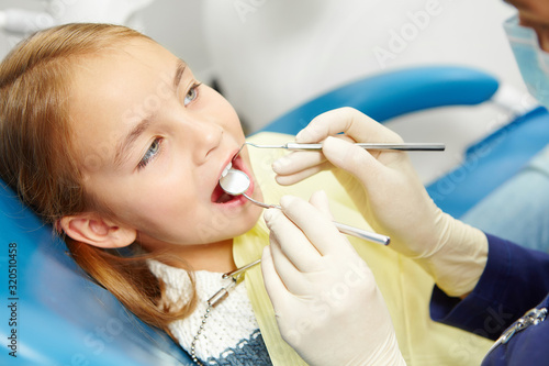 Little caucasian girl sitting in the chair on pediatric dentistry clinic.