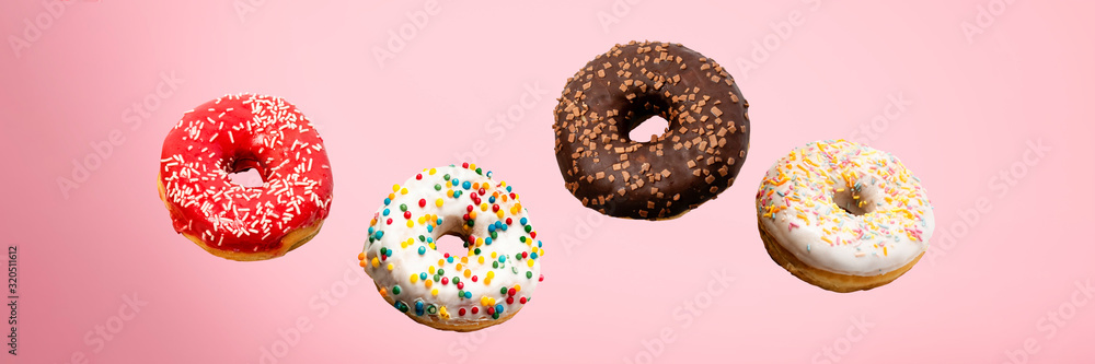 Donuts flying in the air on a pink background. Bakery, baking concept. Levitation. Banner