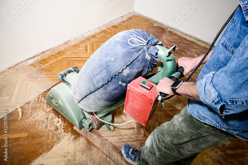 Sanding hardwood floor with the grinding machine. Repair in the apartment.