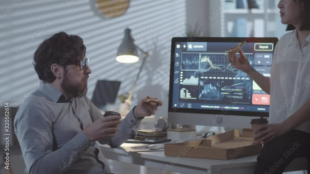 Tracking of happy businessman and Asian businesswoman eating pizza and drinking coffee from to-go cups while taking break from work in office after hours Tracking of happy businessman and Asian businesswoman eating pizza and drinking coffee from to-go cups while taking break from work in office after hours