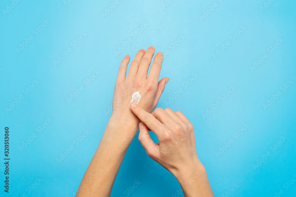 Women's hands. Woman smears cream on her hand on a blue background. The concept of cosmetics, skin care, lotion, makeup, spa. Banner Flat lay, top view Women's hands. Woman smears cream on her hand on a blue background. The concept of cosmetics, skin care, lotion, makeup, spa. Banner Flat lay, top view