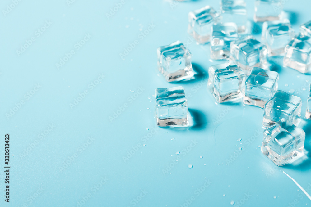 Ice cubes with water on a blue background. Ice concept for drinks. Banner. Flat lay, top view Ice cubes with water on a blue background. Ice concept for drinks. Banner. Flat lay, top view
