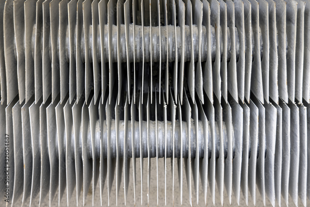 Metal strips on the old radiator grille of the battery, background. Old heating system pipe in the battery Metal strips on the old radiator grille of the battery, background. Old heating system pipe in the battery