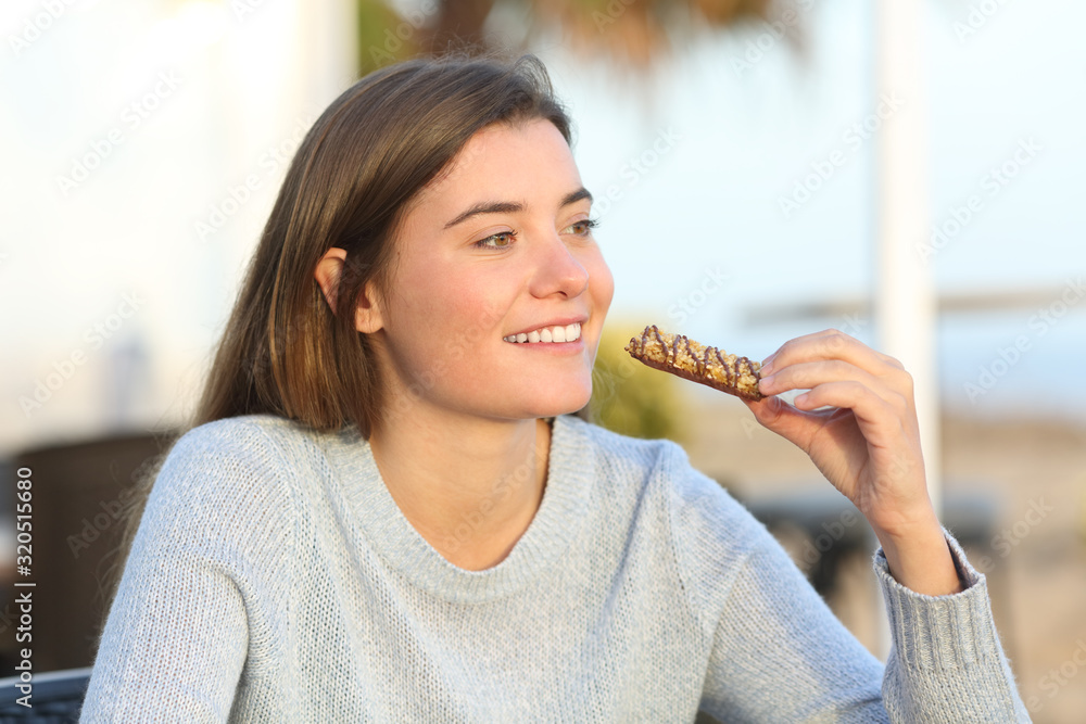 © Antonioguillem - Happy girl eating a snack in a coffee shop terrace